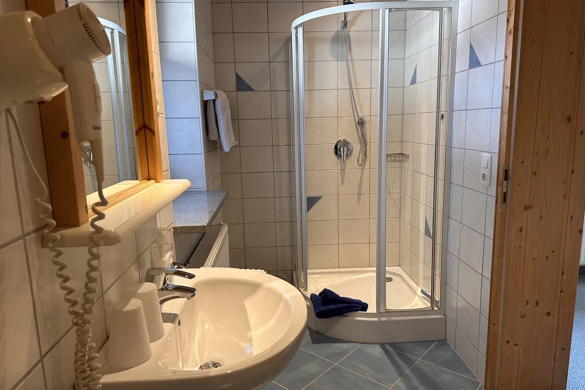 Badezimmer mit Dusche, Waschbecken und Fön