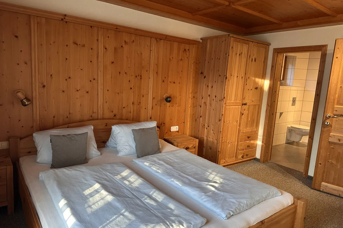 Holzverkleidetes Schlafzimmer mit Doppelbett und Bad